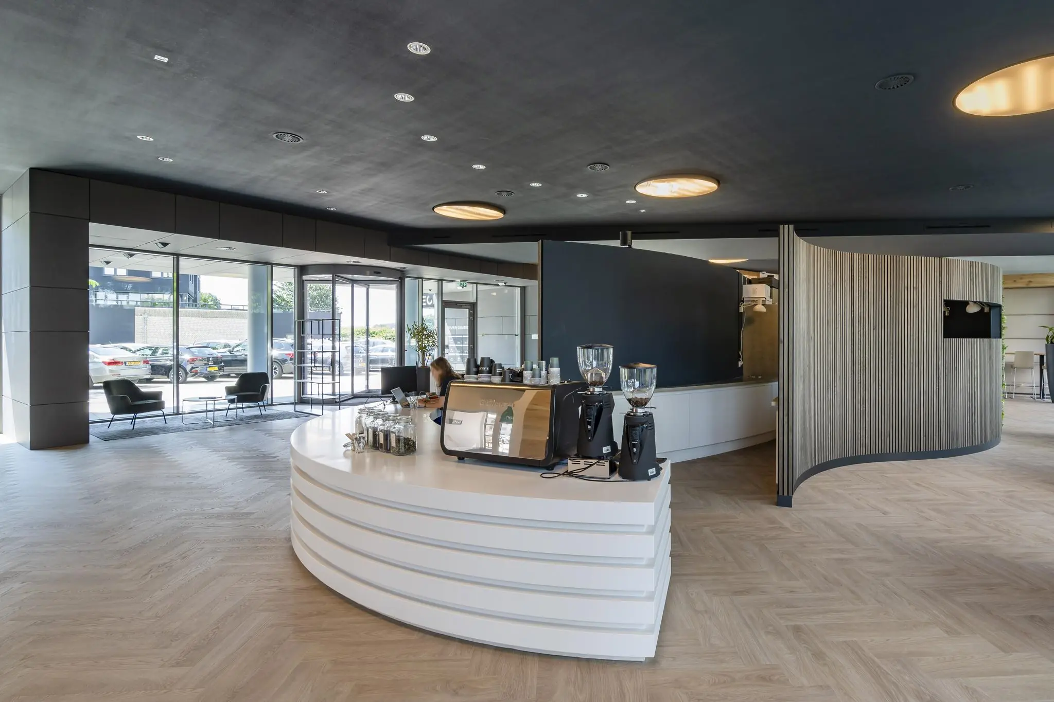 Moderne lobby van het Rivium Quadrant met een strakke koffiebar en zicht op de entree en parkeerplaats.